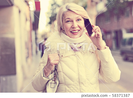 Mature female talking on mobile phone outdoor 58371387