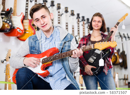 Female and male rock-n-roll players are deciding on suitable amp Female and male rock-n-roll players are deciding on suitable amp 58371507