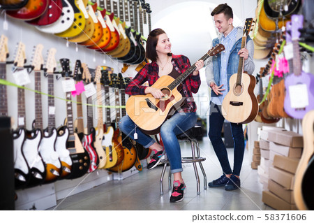 Teenagers examining guitars in shop Teenagers examining guitars in shop 58371606