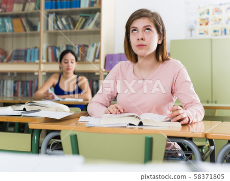 Young girl is thinking about difficult task at the desk Young girl is thinking about difficult task at the desk 58371805
