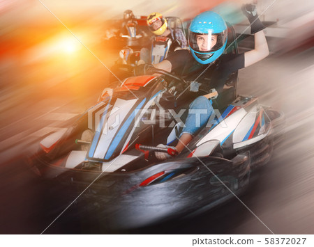 Girl and her friends competing on racing cars at kart circuit 58372027