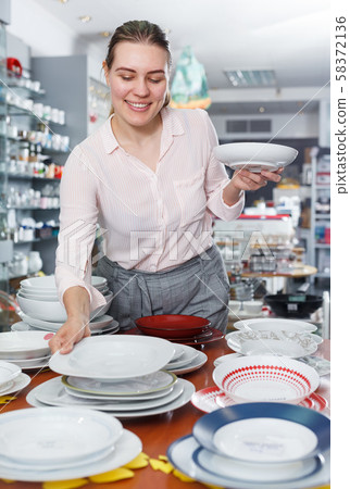 Young woman customer choosing dishes in the tableware store Young woman customer choosing dishes in the tableware store 58372136