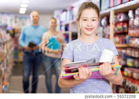 Satisfied girl with family in school accessories store 58372200