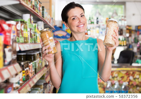 Portrait of woman buying glass jar of beans Portrait of woman buying glass jar of beans 58372356