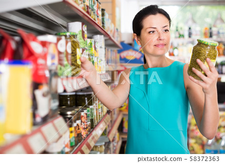Portrait of young female holding jar of green peas Portrait of young female holding jar of green peas 58372363