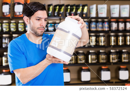 Attractive sportman choosing different sport nutrition products 58372524