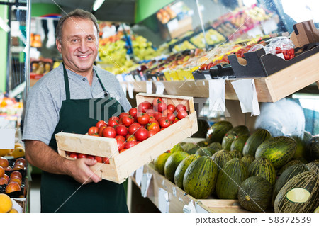 Man seller demonstraiting red tomatos Man seller demonstraiting red tomatos 58372539