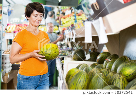 Female is choosing green melon in the supermarket 58372541