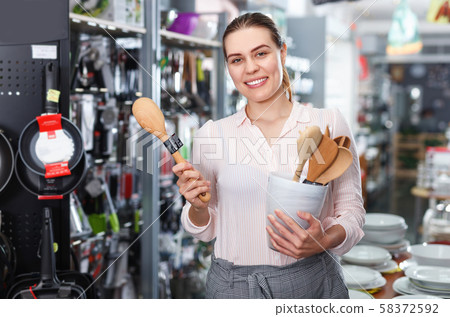 Young woman customer choosing spatula for mix food in the dishes store 58372592