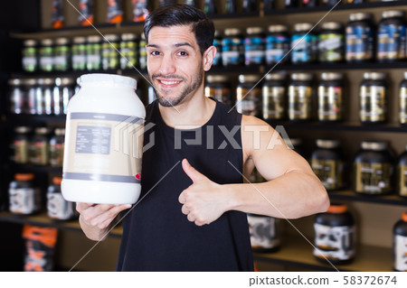 Ordinary sport man holding thumb up in store Ordinary sport man holding thumb up in store 58372674
