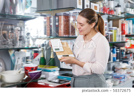 Happy female customer choosing new kitchen scale Happy female customer choosing new kitchen scale 58372675