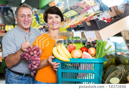Couple standing with basket of purchases Couple standing with basket of purchases 58372698