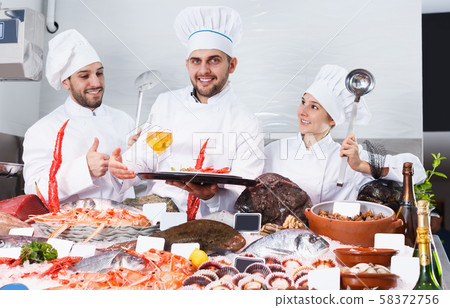 Smiling team of professional cooks of fish restaurant Smiling team of professional cooks of fish restaurant 58372756