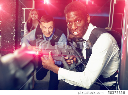 Men and women in business suits playing laser tag emotionally in 58372836