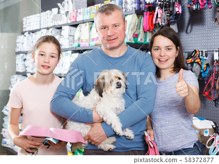 family with little dog in store of pet accessories 58372877