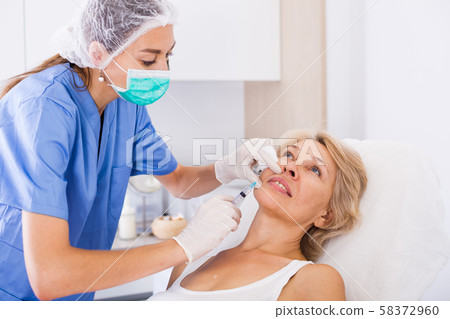 Mature female receiving cosmetic injection 58372960