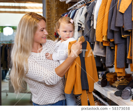 Woman and daughter buying kids clothes Woman and daughter buying kids clothes 58373038