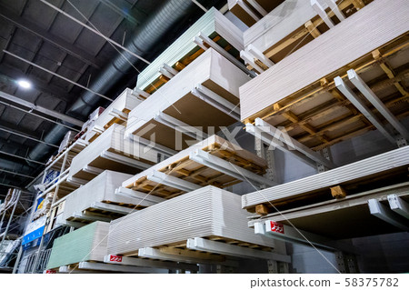 High scale shelving with lots of plywood. High stand with white sheets of drywall 58375782