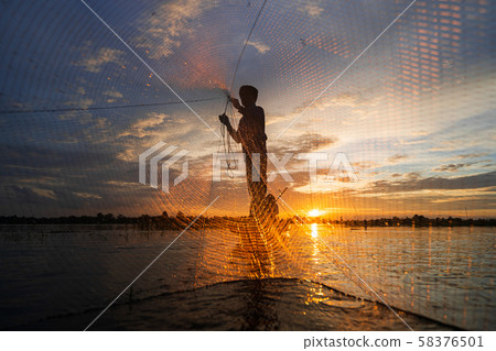 Silhouette Of Traditional Fishermen Throwing Net Fishing At