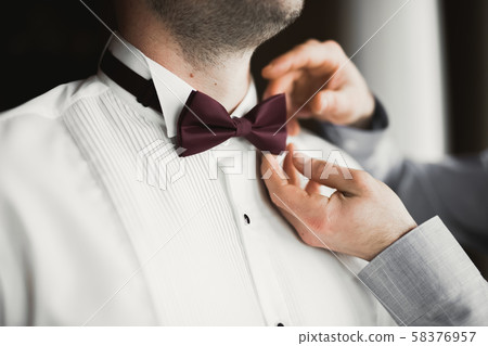 Grooms morning preparation. Handsome man getting dressed and preparing for the wedding Grooms morning preparation. Handsome man getting dressed and preparing for the wedding 58376957