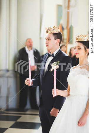 Bride and groom holding candles in church 58377087