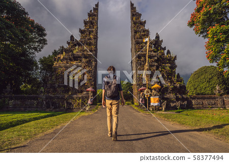 Tourist man walking through Traditional Balinese Hindu gate Candi Bentar close to Bedugul, Bratan Tourist man walking through Traditional Balinese Hindu gate Candi Bentar close to Bedugul, Bratan 58377494