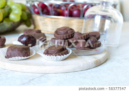 Homemade raw chocolate sweet candies with raspberries inside lay on round kitchen board on white 58377547