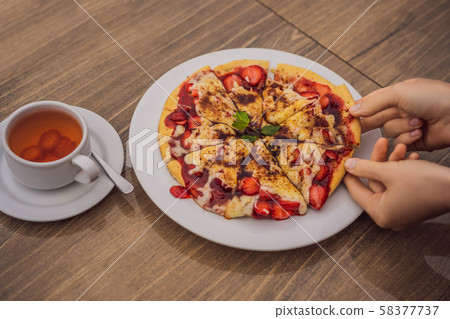 Woman eating delicious strawberry pizza on a balinese tropical nature background. Bali island Woman eating delicious strawberry pizza on a balinese tropical nature background. Bali island 58377737