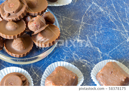 Homemade raw chocolate sweet candies with raspberries inside on Blue background with copy space Homemade raw chocolate sweet candies with raspberries inside on Blue background with copy space 58378175