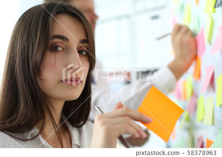 Pretty female office worker holding sticky paper looking in camera Pretty female office worker holding sticky paper looking in camera 58378963