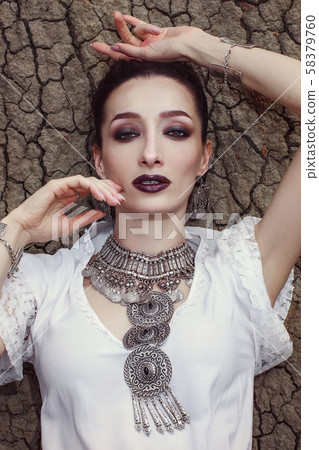 Portrait of a girl lying on a cracked, dry ground. 58379760