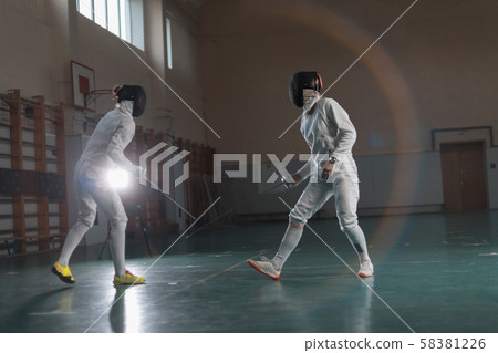A portrait of two young women fencers in the hemlets training A portrait of two young women fencers in the hemlets training 58381226
