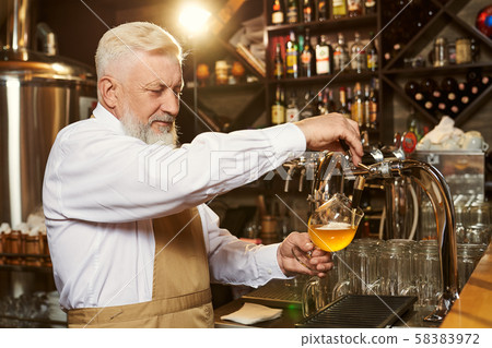Barman pouring light beer in glass with beer tap. Barman pouring light beer in glass with beer tap. 58383972
