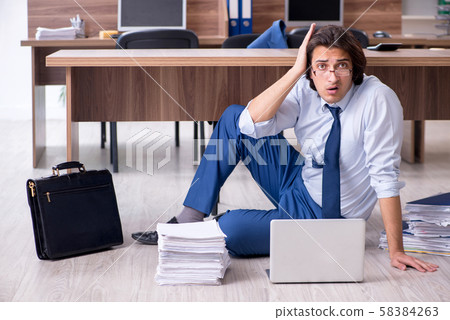 Young male employee and too many work in the office Young male employee and too many work in the office 58384263