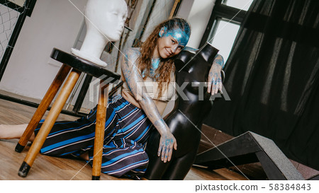 Long-haired beautiful artist in workshop with mannequins 58384843