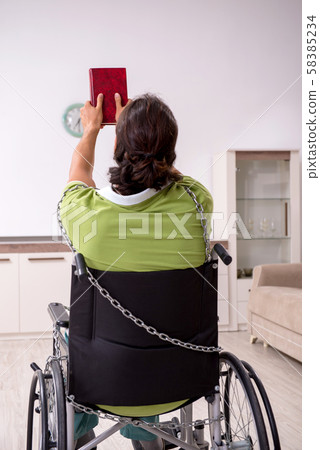 Young male invalid in wheel-chair suffering at home Young male invalid in wheel-chair suffering at home 58385234
