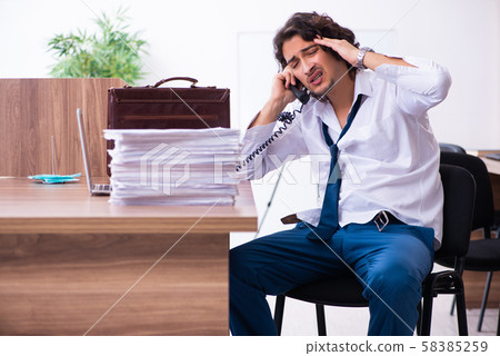 Young male employee unhappy with excessive work 58385259