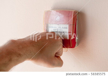 Male fist breaks a fire alarm button Male fist breaks a fire alarm button 58385575