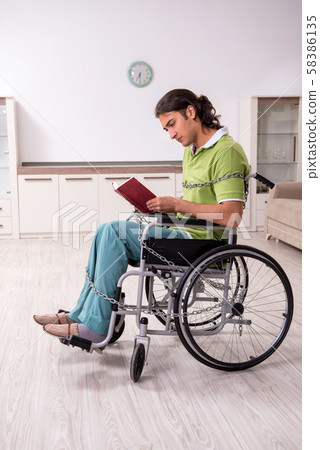 Young male invalid in wheel-chair suffering at home 58386135