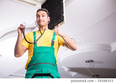 Young repairman repairing ceiling air conditioning unit Young repairman repairing ceiling air conditioning unit 58386353