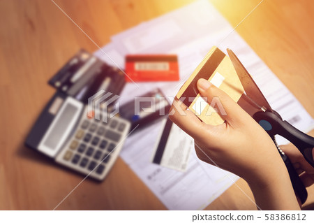 women use scissors to cut credit cards in hand with many credit card and statement on table for background 58386812