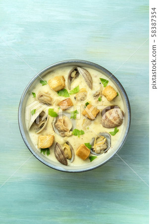 Clam chowder with fresh parsley and croutons, shot from the top on a blue background with a place 58387354