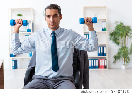 Young handsome employee doing sport exercises at workplace Young handsome employee doing sport exercises at workplace 58387378