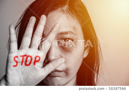 stop violence against women campaign. Asia woman with bruise on arms and face raised her hand for dissuade, hand write the word STOP in red color. 58387566