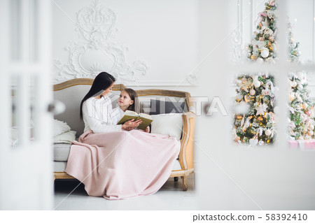Caring mother decided to read to her child an interesting book on Christmas Eve Caring mother decided to read to her child an interesting book on Christmas Eve 58392410