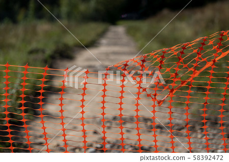 Perforated fence on a dirt road in autumn 58392472