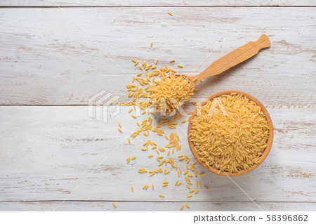 Raw orzo (risoni) pasta in wooden bowl. Close up Raw orzo (risoni) pasta in wooden bowl. Close up 58396862