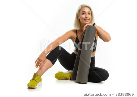 A young sports girl with blonde hair and bright manicure in a black sports top, leggings and yellow 58398069