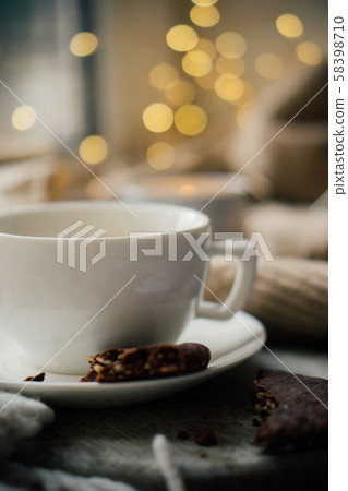 Cup of coffe with milk and chocolate cookies on warm wool blanket, cozy winter home Cup of coffe with milk and chocolate cookies on warm wool blanket, cozy winter home 58398710