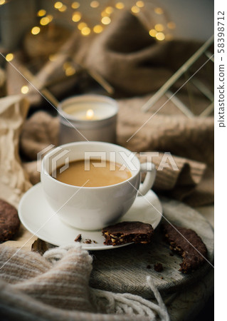 Cup of coffe with milk and chocolate cookies on warm wool blanket, cozy winter home Cup of coffe with milk and chocolate cookies on warm wool blanket, cozy winter home 58398712